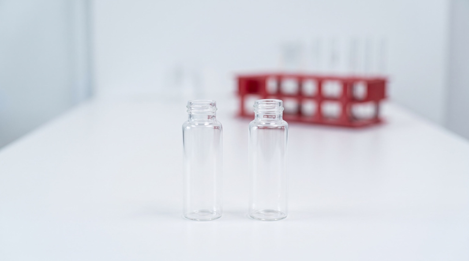 Dos viales de vidrio sin etiqueta sobre mesa de laboratorio blanca